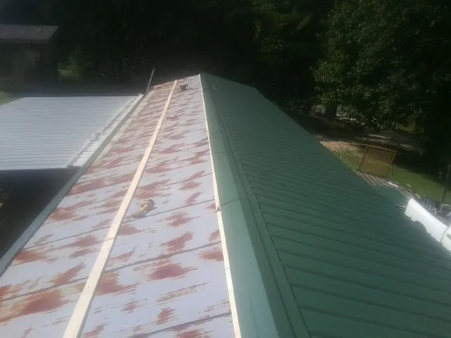 Old rusted panels beside newly installed green metal roofing — Wind Damage Roof Repair by Roofing Brothers in East Rockaway