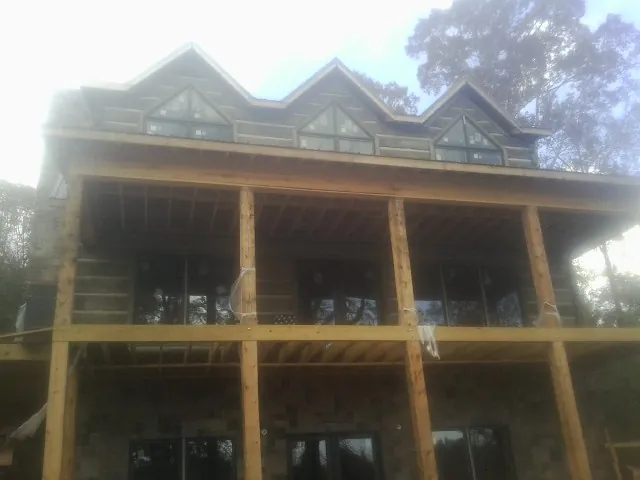 Dormers and porch framing on a large log home under construction — Roof Coating work by our crew in East Rockaway