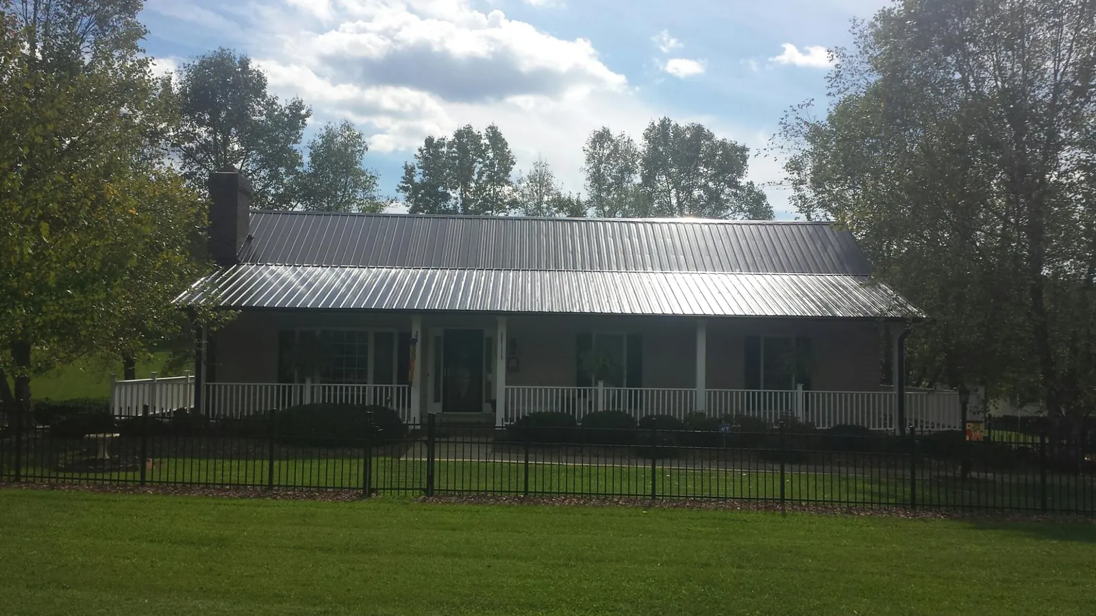 Gray metal roof on a brick ranch with a full width front porch — Gutter Guard Installation work by our crew in East Rockaway