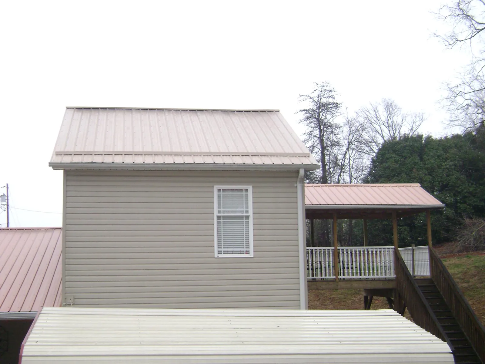 Tan metal roofs on a two story addition and attached porch, from a Roof Replacement job in East Rockaway